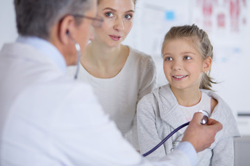 Girl and doctor with stethoscope listening to heartbeat