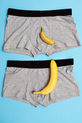 baby banana compare size with big banana on male panties on blue background.