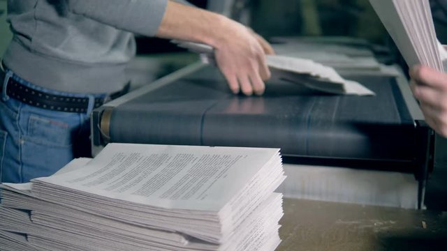 Men work with paper, stacking it, close up.