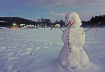 Snowman in a white country at an evening