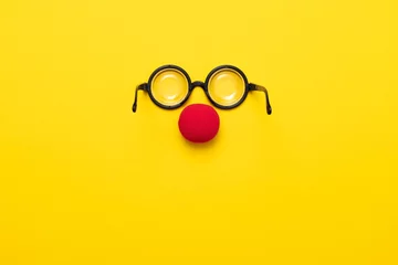 Deurstickers Funny glasses, red clown nose and tie lie on a colored background, like a face. © RealPeopleStudio