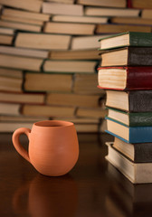 cup and many books on a wooden table