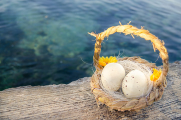 small basket with two easter eggs on the sea doc on golden hour