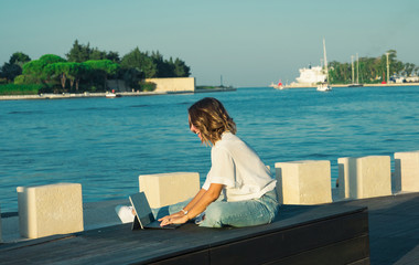 Young woman is using laptop on the bench outdoor