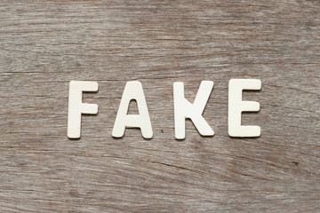Alphabet letter in word fake on wood background