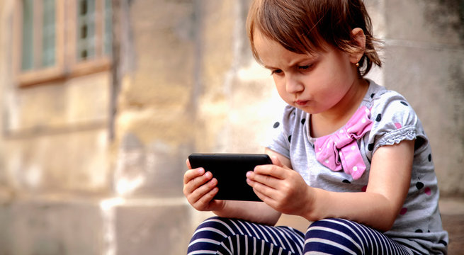 Psychological problems of social media addiction. Little child girl holding smart phone