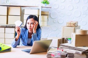 Young  Asia Businesswoman use laptop. She is use laptop for order online and show credit cards. She  is sad and unhappy.E-commerce , Shopping , Photo concept work and Business.