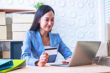 Young  Asia Businesswoman use laptop. She is use laptop for order online and show credit cards. She  is smile and happy.E-commerce , Shopping , Photo concept work and Business.