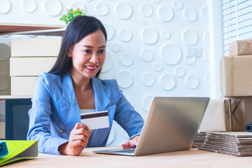 Young  Asia Businesswoman use laptop. She is use laptop for order online and show credit cards. She  is smile and happy.E-commerce , Shopping , Photo concept work and Business.