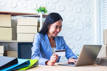 Young  Asia Businesswoman use laptop. She is use laptop for order online and show credit cards. She  is smile and happy.E-commerce , Shopping , Photo concept work and Business.