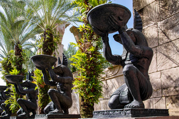 Alley with large identical stone statues of the Egyptian God Anubis on a summer sunny day