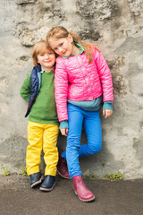 Obraz na płótnie Canvas Outdoor portrait of two little kids, brother and sister, wearing colorful clothes
