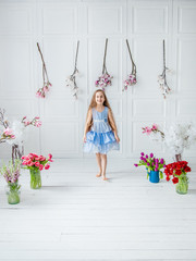 Portrait of a beautiful blue-eyed girl, a little girl among spring flowers in a bright room.