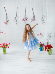 Portrait of a beautiful blue-eyed girl, a little girl among spring flowers in a bright room.
