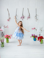 Portrait of a beautiful blue-eyed girl, a little girl among spring flowers in a bright room.