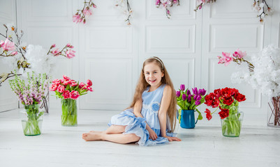Portrait of a beautiful blue-eyed girl, a little girl among spring flowers in a bright room.