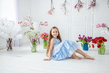 Portrait of a beautiful blue-eyed girl, a little girl among spring flowers in a bright room.