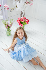 Portrait of a beautiful blue-eyed girl, a little girl among spring flowers in a bright room.