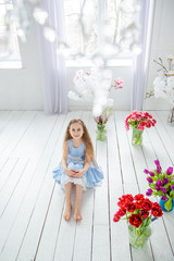 Portrait of a beautiful blue-eyed girl, a little girl among spring flowers in a bright room.