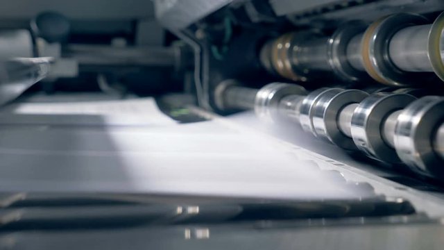 Printed sheets moving on automated conveyor, close up.