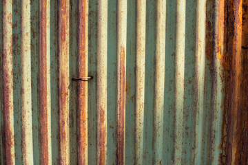 Old green and rusty galvanized, corrugated iron siding vintage texture background of grunge. Image taken with beautiful sun light cast on.