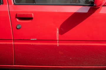 Close-up of dirty bird stain shit dropping on red sedan car door and window. Selective focus.