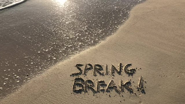 Spring Break message handwritten in smooth sand on bright tropical beach