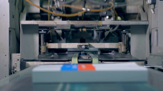 Many books move on a line in a typography facility, close up.