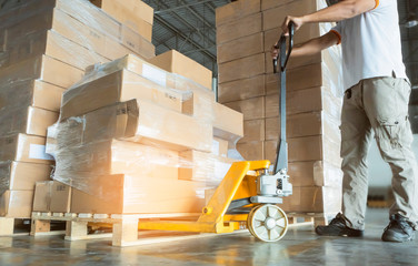 Workers Using Hand Pallet Jack Unloading Package Boxes at Storage Warehouse. Delivery Shipment Boxes. Trucks Loading at Dock Warehouse. Supply Chain. Warehouse Shipping Transport and Logistics.
