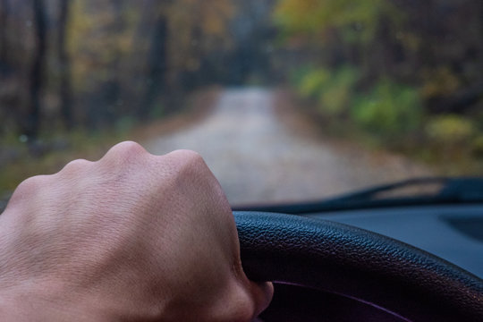 Hand Driving Car Down Gravel Road.