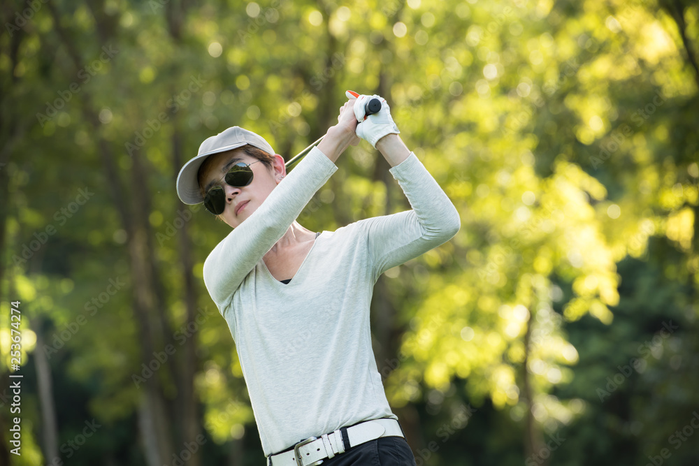 Wall mural asian woman playing golf on a beautiful natural golf course