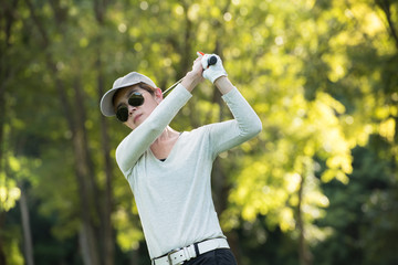 Asian woman playing golf on a beautiful natural golf course