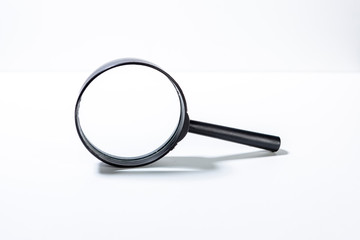 Magnifying glass lit from above casting a short shadow just in front of it. Clean studio shot currency with magnify tool 