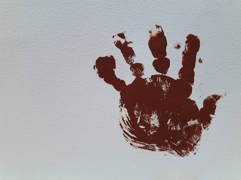 Painted baby hand with over a textured-white sheet. Background.