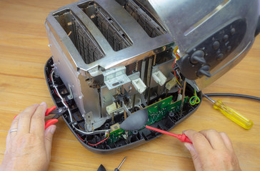 Concept Right to Repair, image showing hands of consumer repairing toaster with tools. Reduce waste...