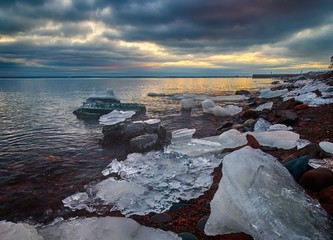 Snow and Ice on Rocks in sea at sunset during winter