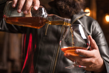 Handsome man holding a glass of whisky. Sipping whiskey. Degustation, tasting. Man holding a glass of whisky.