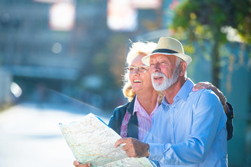 Senior couple of tourists looking at city map