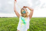 Fun, happy, people and holidays concept - Young cheerful woman at Holi paint party