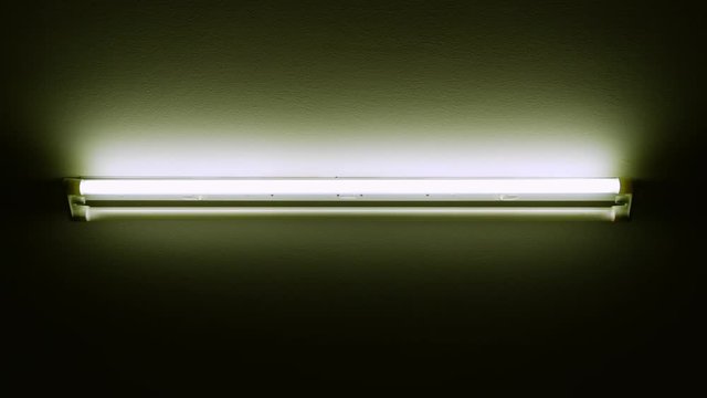 Double cold neon light turning off and on, on the ceiling of a dark, cold room.