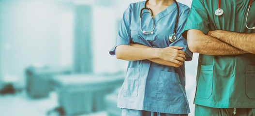 Two hospital staffs - surgeon, doctor or nurse standing with arms crossed in the hospital. Medical...