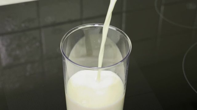 Closeup pouring milk into a measuring cup making it easy to use in a pastry or menu.
