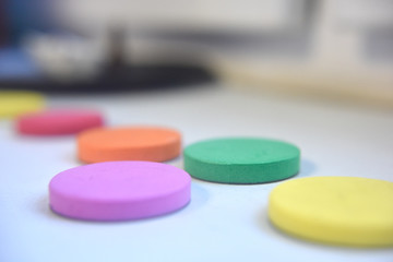 Spongy round flat items of different colours on the white background indoor