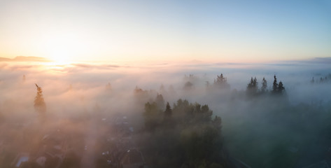 Aerial view of a residential neighborhood covered in a layer of fog during a vibrant sunrise. Taken...