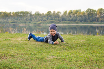 Naklejka na ściany i meble Children and childhood concept - Smiling little boy laying on the grass