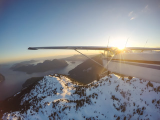 Small airplane flying near the rocky Candian Mountains during a vibrant sunset. Taken near Squamish, North of Vancouver, British Columbia, Canada.