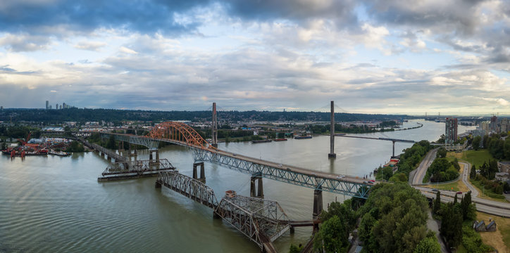Aerial panoramic view of Pattullo and Skytrain Bridge going across Fraser River duing a cloudy evening before sunset. Taken in New Westminster, Vancouver, BC, Canada.