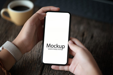 Woman holding blank screen mobile smartphone on old wood table