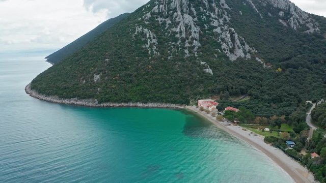 Beautiful panoramic view of Divna coastline with its crystalline waters and some buildings. Cres Island. Croatia. Aerial view traveling tilt down