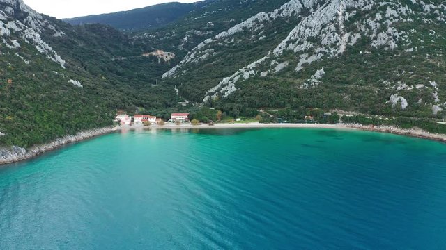 Detail of buildings at Divna beach and its clear waters. Cres Island. Croatia. Aerial view tilt down